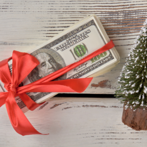 A stack of bills wrapped in a red bow next to a Christmas tree